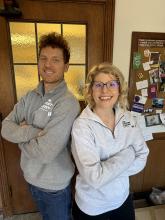 LSJ Academic Advisers pictured on the left Jonathan Fincher in a grey quarter zip LSJ sweatshirt with arms folded across check with Kat Eli on the right in a white quarter zip LSJ sweatshirt with arms folded across chest.